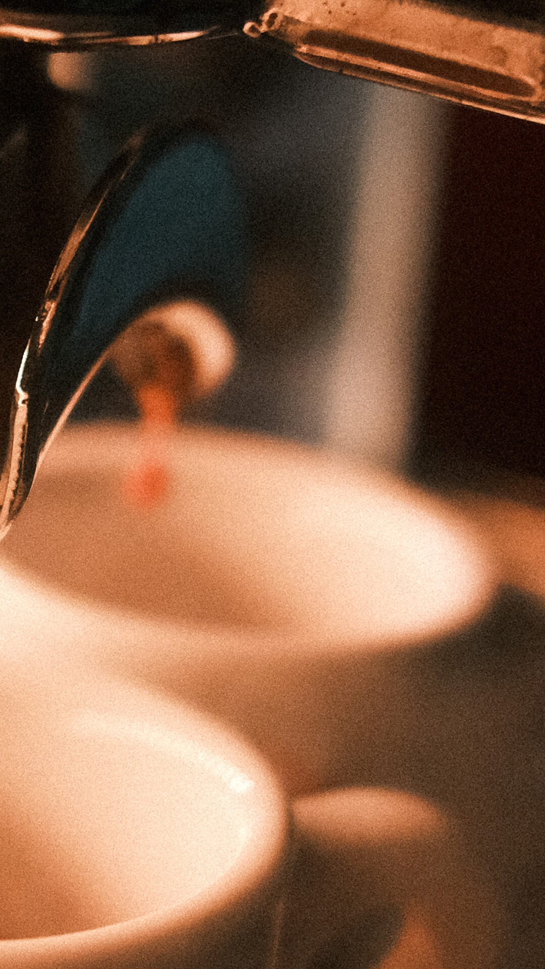 Zu sehen ist im Vordergrund der Doppelauslauf eines Siebträgers aus dem Kaffee tröpfeln anfängt. Darunter sind leicht verschwommen 2 weiße Espressotassen zu erkennen.