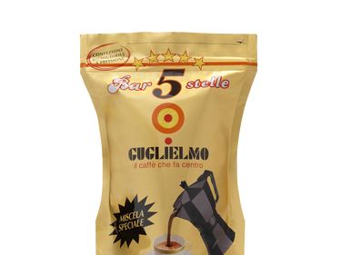 Eine goldene wiederverschließbare Aromaverpackung für den gemahlenen Mokka Kaffee Guglielmo Bar 5 Stelle Oro. In der Mitte sieht man das Logo von Guglielmo mit dem orange,gelb, roten konzentrischen Kreis. Darunter ist eine Aluminium Mokkakanne abgebildet welche frisch gebrühten Kaffee in eine weiße Tasse eingießt. Darüber befindet sich der weiße Schiftzug mit rotem Rand Bar 5 Stelle mit 5 gelben Sternen darüber.