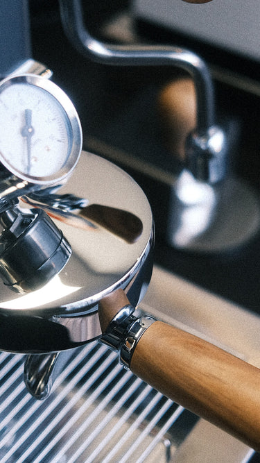 Eine Detailaufnahme der Elba Gentile. Zu sehen ist die Faema E-61 Brühgruppe mit Olivenholz Siebträger. Das zentrale Detail ist das auf der Brühgruppe angebrachte Brühdruck Manometer.
