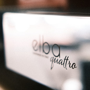 Eine Detailaufnahme der Abtropftasse einer Espressomaschine mit der Aufschrift „Elba Quattro“. 