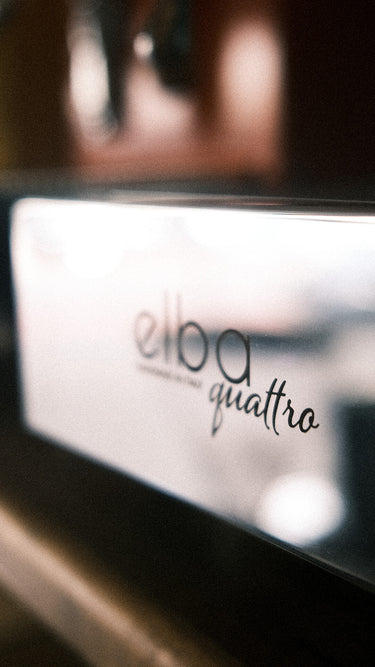 Eine Detailaufnahme der Abtropftasse einer Espressomaschine mit der Aufschrift „Elba Quattro“. 