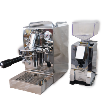 Zu sehen ist die Espressomaschine Quickmill Carola Evo in Edelstahl. In der Brühgruppe ist ein Siebträger mit schwarzem Kunststoffgriff für 2 Tassen eingespannt auf der rechten Seite die einstellbare PID Temperaturkontrolle. Rechts oben befindet sich das Brühdruck-Manometer. Darunter die herausziehbare Abtropftasse. Darüber eine Reling um das Herunterfallen der Tassen zu vermeiden. Daneben ist die On-Demand Kaffeemühle Eureka Mignon Silenzio in chrom abgebildet.