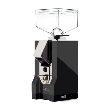 Die On-Demand Kaffeemühle Eureka Mignon Silenzio in matt schwarz mit verchromtem Auslauf. Am schwarzem Sockel befinden sich rechts unten der umschaltbare Druckknopf für  Timer oder manuellen Betrieb, sowie das Drehrad für die Einstellung der Mahldauer bei Timerbetrieb. 