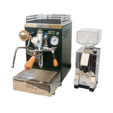 Zu sehen ist die Espressomaschine Elba Quattro in British Racing Green mit Siebträgergriff, Kipphebelknauf und Drehrad für Dampf aus Olivenholz. In der Mitte der Brühgruppe befindet sich ein Brühdruck Manometer, auf der rechten Seite das Kesseldruck-Manometer. Darunter die abnehmbare Abtropftasse. Darüber eine Reling um das Herunterfallen der Tassen zu vermeiden. Daneben ist die On-Demand Kaffeemühle Eureka Mignon Silenzio in chrom abgebildet.