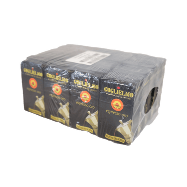 Eine Steige mit 20 Stück schwarzer Vakuumverpackungen für den gemahlenen Mokka Kaffee Guglielmo Oro. Bei jeder Packung sieht man oben den goldenen Schriftzug Guglielmo il caffè che fa centro, darunter das Logo mit dem orange, gelb, roten konzentrischen Kreis. In der Mitte steht espresso oro. Darunter ist eine schräge Aluminium Mokkakanne abgebildet. Unten die Aufschrift Gusto Delicato