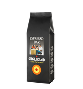 Eine schwarze Aromaverpackung für den Kaffee Guglielmo Espresso Barr in Bohnen.  Oben ist der weiße Schriftzug Espresso Bar zu lesen. In der Mitte ein Bild von 2 Frauen und einem Mann die an einem Tisch sitzen und Kaffee trinken. Darunter der Schriftzug Guglielmo il caffè che fa centro. Unten sieht man das Logo mit dem orange, gelb, roten konzentrischen Kreis.