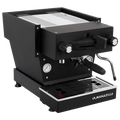 Die Schrägansicht von vorne der Espressomaschine La Marzocco Linea Mini R in matt schwarz. An der Oberseite ist das Paddle für den Kaffeebezug angebracht, links davon das Drehrad für Teewasser, rechts davon das Drehrad für die Dampflanze. Darunter befindet sich die Brühgruppe mit dem eingespannten Siebträger mit schwarzem Griff, darunter die Abtropftasse.