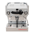 Die Vorderansicht von vorne der Espressomaschine La Marzocco Linea Mini R in chrom. An der Oberseite ist das Paddle für den Kaffeebezug angebracht, links davon das Drehrad für Teewasser, rechts davon das Drehrad für die Dampflanze. Darunter befindet sich die Brühgruppe mit dem eingespannten Siebträger mit schwarzem Griff, darunter die Abtropftasse.