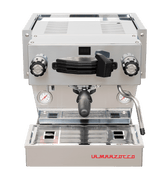 Die Vorderansicht von vorne der Espressomaschine La Marzocco Linea Mini R in chrom. An der Oberseite ist das Paddle für den Kaffeebezug angebracht, links davon das Drehrad für Teewasser, rechts davon das Drehrad für die Dampflanze. Darunter befindet sich die Brühgruppe mit dem eingespannten Siebträger mit schwarzem Griff, darunter die Abtropftasse.