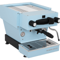 Die Schrägansicht von vorne der Espressomaschine La Marzocco Linea Mini R in hellblau. An der Oberseite ist das Paddle für den Kaffeebezug angebracht, links davon das Drehrad für Teewasser, rechts davon das Drehrad für die Dampflanze. Darunter befindet sich die Brühgruppe mit dem eingespannten Siebträger mit schwarzem Griff, darunter die Abtropftasse.