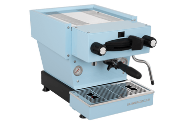 Die Schrägansicht von vorne der Espressomaschine La Marzocco Linea Mini R in hellblau. An der Oberseite ist das Paddle für den Kaffeebezug angebracht, links davon das Drehrad für Teewasser, rechts davon das Drehrad für die Dampflanze. Darunter befindet sich die Brühgruppe mit dem eingespannten Siebträger mit schwarzem Griff, darunter die Abtropftasse.