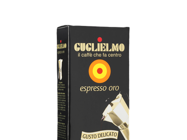 Eine schwarze Vakuumverpackung für den gemahlenen Mokka Kaffee Guglielmo Oro. Oben sieht man den goldenen Schriftzug Guglielmo il caffè che fa centro, darunter das Logo mit dem orange, gelb, roten konzentrischen Kreis. In der Mitte steht espresso oro.
Darunter ist eine schräge Aluminium Mokkakanne abgebildet. Unten die Aufschrift Gusto Delicato.