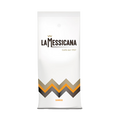 Eine weiße Kaffeepackung für Bohnen mit Aromaventil. Im oberen Teil befindet sich der schwarze Schriftzug La Messicana. Über dem M ist eine goldene Zick-zack Linie aufgedruckt, unter dem Logo in goldener Schrift Caffè dal 1957. Im unteren Teil sieht man eine über die ganze Breite verlaufende gold/orange/schwarze Zick-zack Linie. Darunter steht der orange Schriftzug Sunrise.